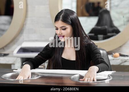 Hübsches junges indisches Mädchen sitzt in einem Salon für Maniküre, Beauty-Salon-Konzept, Schönheit und Gesundheitswesen Konzept. Stockfoto