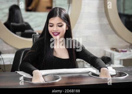 Hübsches junges indisches Mädchen sitzt in einem Salon für Maniküre, Beauty-Salon-Konzept, Schönheit und Gesundheitswesen Konzept. Stockfoto