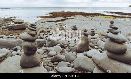 Gestapelte Felsen in eine stehende stille Formation, Kieselsteine am Strand legen sich so hoch wie möglich aufeinander, Steingruppen in senkrechter Position Stockfoto