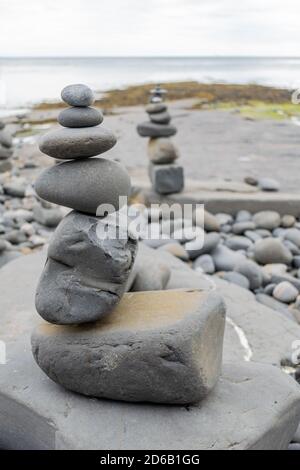 Gestapelte Felsen in eine stehende stille Formation, Kieselsteine am Strand legen sich so hoch wie möglich aufeinander, Steingruppen in senkrechter Position Stockfoto
