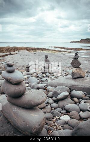 Gestapelte Felsen in eine stehende stille Formation, Kieselsteine am Strand legen sich so hoch wie möglich aufeinander, Steingruppen in senkrechter Position Stockfoto