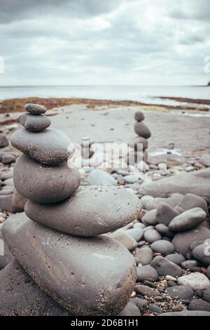 Gestapelte Felsen in eine stehende stille Formation, Kieselsteine am Strand legen sich so hoch wie möglich aufeinander, Steingruppen in senkrechter Position Stockfoto