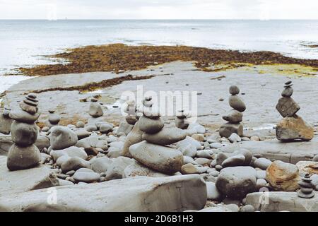 Gestapelte Felsen in eine stehende stille Formation, Kieselsteine am Strand legen sich so hoch wie möglich aufeinander, Steingruppen in senkrechter Position Stockfoto