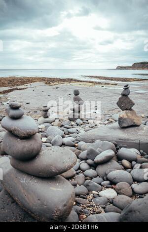 Gestapelte Felsen in eine stehende stille Formation, Kieselsteine am Strand legen sich so hoch wie möglich aufeinander, Steingruppen in senkrechter Position Stockfoto