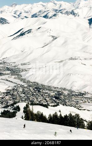 Skifahrer auf den schneebedeckten Hängen des bald Mountain haben einen Blick aus der Vogelperspektive auf das Wood River Valley, das die benachbarten Ferienorte Ketchum und Sun Valley beherbergt, zwei beliebte Urlaubsziele in Idaho, USA. Während der Wintersaison transportieren zahlreiche Sessellifte und Gondelkabinen Skifahrer, Snowboarder und Touristen die verschneiten Berghänge hinauf zu Loipenköpfen und malerischen Panoramen der Smoky Mountains. Stockfoto