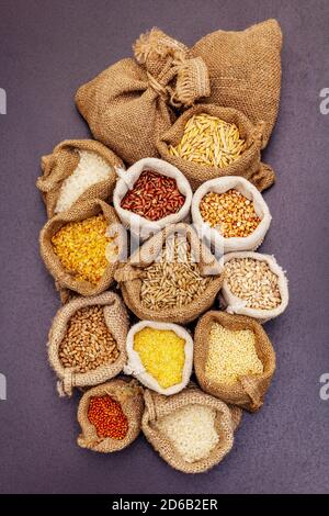 Verschiedene Müslisorten. Eine unverzichtbare Zutat für eine gesunde Ernährung. Handgemachte Taschen, schwarzer Stein Beton Hintergrund, Draufsicht Stockfoto