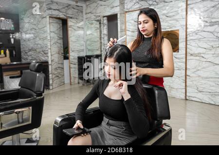 Portrait einer weiblichen Friseur stehen und machen Frisur von einer niedlichen schönen jungen Frau in Schönheitssalon, Schönheitssalon Konzept. Stockfoto