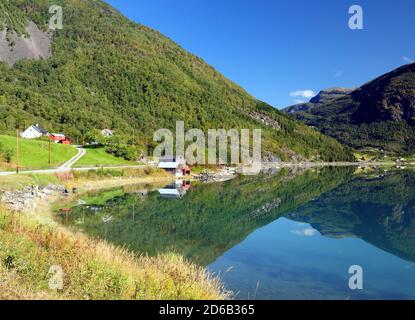 Berge, Die Sich Im Ruhigen Wasser Des Dalsfjords In Der Nähe Spiegeln Skjolden an EINEM sonnigen Sommertag mit EINEM klaren Blau Himmel und EIN paar Wolken Stockfoto