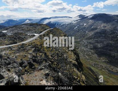 Kurvenreiche Straße Von Dalsnibba In Das Karge Tal Umgeben Von Gletscherbedeckte Berge zum Geirangerfjord an EINEM sonnigen Sommertag Mit EINEM klaren blauen S Stockfoto