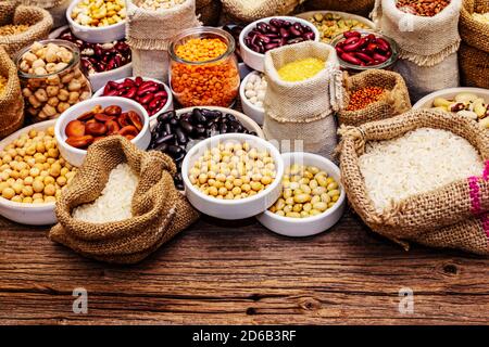 Verschiedene Arten von Bohnen und Getreide Körner. Set von unverzichtbaren Proteinquellen für einen gesunden Lebensstil. Alter Holztisch Stockfoto