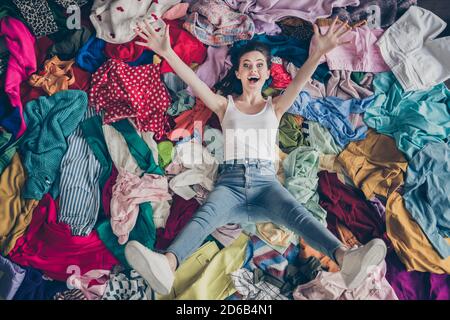 Hoher Winkel über Ansicht Foto von verrückten lustige Dame Frühling Reinigung Haushalt liegen viele Kleidung Haufen Stapel Boden heben die Arme Legs Shopper umgeben Verkäufe Stockfoto