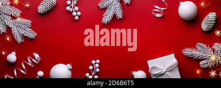 Weihnachtskugeln, Geschenkbox und Tannenzweig auf rotem Hintergrund Stockfoto