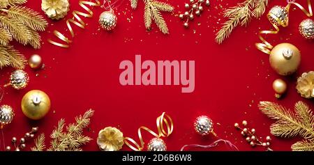 Goldene Weihnachtskugeln und Tannenzweig auf rotem Hintergrund Stockfoto