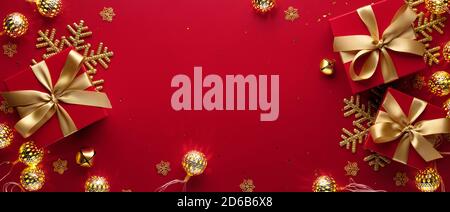 Goldene Weihnachtskugeln, Schneeflocke und Geschenkbox auf rotem Hintergrund Stockfoto