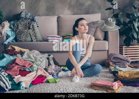 In voller Länge Foto von frustriert Mädchen sitzen Boden Teppich aussehen Wollen Sie nicht saubere Wäsche riesige chaotisch verwendet Dressing im Haus In Innenräumen Stockfoto