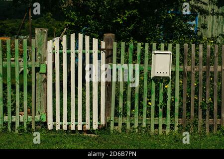 Ein alter grüner Holzzaun mit einem Wicket und einem Briefkasten. Rustikal. Ländlich. Stockfoto