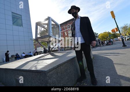 Ein orthodoxer jüdischer Mann, der eine Gesichtsmaske trägt, posiert neben einer Metallskulptur eines Dreidels gegenüber dem Welthauptsitz der Chabad-Lubavitch-Synagoge, außerhalb der ausgewiesenen „heißen Zonen“ (wo Spitzen in Coronavirus-Infektionen entdeckt wurden), im Brooklyn-Bezirk von New York City, NY, 15. Oktober 2020. Chabad - Lubavitch Gemeinschaft hat keine Spitze in COVID-19 Infektionen gesehen, aber andere in der Nähe heiße Zonen haben, was New York Gov. Andrew Cuomo beginnt mit der Einführung neuer Beschränkungen. (Anthony Behar/Sipa USA) Stockfoto