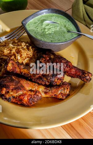 Peruanische Hühnerschenkel mit Aji verde grüner Koriander-Sauce und gebratenem Reis Stockfoto