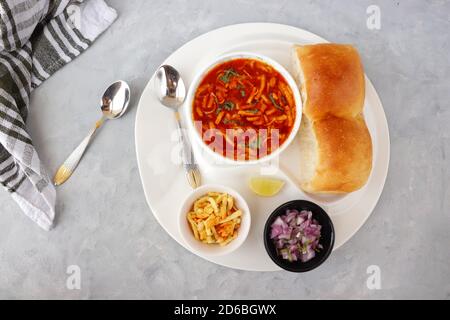 Spicy Misal Pav oder Sal Pav ist ein traditioneller Snack oder Chaat-Essen aus Maharashtra, Indien. Serviert mit gehackten Zwiebeln, Zitronenkeilchen und farsan. Stockfoto