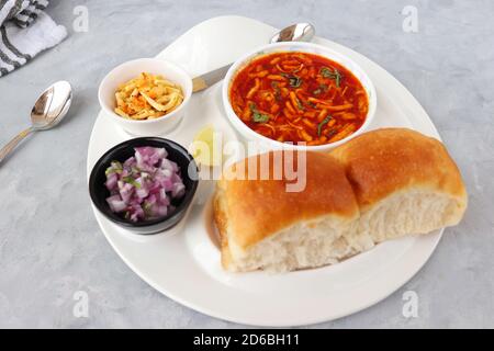 Spicy Misal Pav oder Sal Pav ist ein traditioneller Snack oder Chaat-Essen aus Maharashtra, Indien. Serviert mit gehackten Zwiebeln, Zitronenkeilchen und farsan. Stockfoto