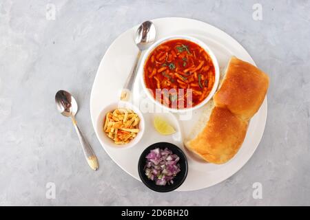 Spicy Misal Pav oder Sal Pav ist ein traditioneller Snack oder Chaat-Essen aus Maharashtra, Indien. Serviert mit gehackten Zwiebeln, Zitronenkeilchen und farsan. Stockfoto