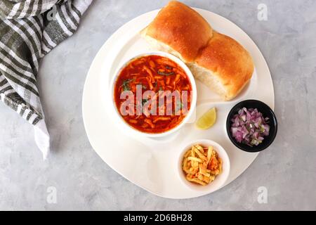 Spicy Misal Pav oder Sal Pav ist ein traditioneller Snack oder Chaat-Essen aus Maharashtra, Indien. Serviert mit gehackten Zwiebeln, Zitronenkeilchen und farsan. Stockfoto