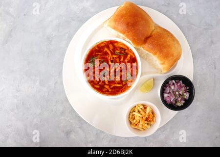 Spicy Misal Pav oder Sal Pav ist ein traditioneller Snack oder Chaat-Essen aus Maharashtra, Indien. Serviert mit gehackten Zwiebeln, Zitronenkeilchen und farsan. Stockfoto