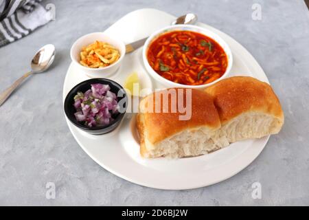 Spicy Misal Pav oder Sal Pav ist ein traditioneller Snack oder Chaat-Essen aus Maharashtra, Indien. Serviert mit gehackten Zwiebeln, Zitronenkeilchen und farsan. Stockfoto