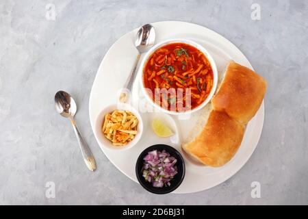 Spicy Misal Pav oder Sal Pav ist ein traditioneller Snack oder Chaat-Essen aus Maharashtra, Indien. Serviert mit gehackten Zwiebeln, Zitronenkeilchen und farsan. Stockfoto