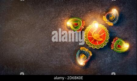 Draufsicht über Ton beleuchtet Licht ein Feuer bereits auf Diya oder Öllampe, Studio auf Beton Hintergrund geschossen, Dekoration des Hinduismus rangoli, Happy celebra Stockfoto