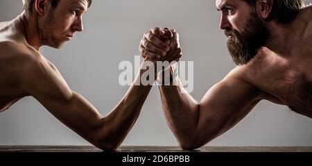 Zwei Männerhände umklammten Arm Wrestling, stark und schwach, ungleiche Übereinstimmung. Stark muskulös bärtigen Mann Arm Ringen ein mickrigen schwachen Mann Stockfoto