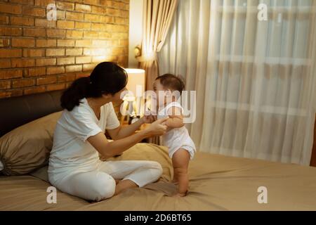 Asiatische Mutter spielt mit ihrem Baby auf dem Bett Stockfoto