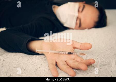 Close-up auf dem Boden der Spritze mit dem Medikament. Im Hintergrund, ein junger Drogenabhängiger Stockfoto