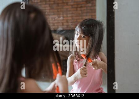 Porträt eines Mädchens, das vor einem Spiegel die Haare kämmt. Konzept der Schönheit, Mode, Selbstversorgung, tägliche Angelegenheiten, echtes Leben Stockfoto