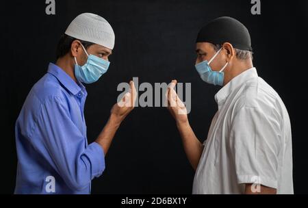 Zwei muslimische Männer in medizinischer Maske Gruß oder salam jeder Andere in islamischer Weise unter Beibehaltung der sozialen Distanzierung - Konzept Von Coronavirus oder covid-19 Stockfoto