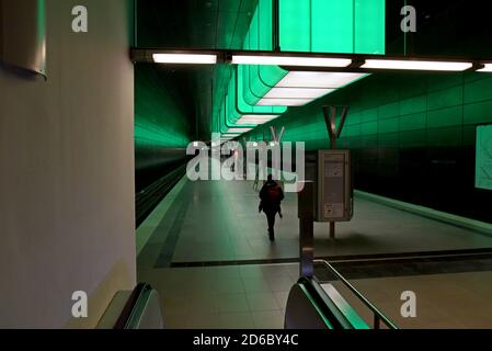 Passagiere, die unter der dramatischen Farbveränderungs-Beleuchtung auf Züge warten Am Bahnhof HafenCity Universität an der U-Bahn Hamburg Stockfoto