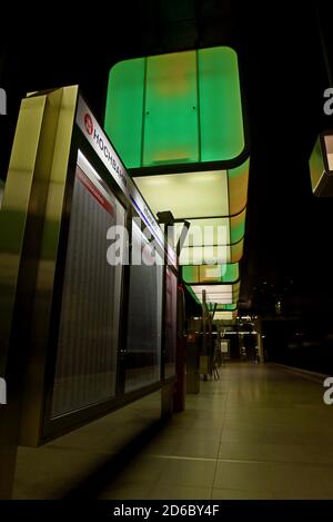 Passagiere, die unter der dramatischen Farbveränderungs-Beleuchtung auf Züge warten Am Bahnhof HafenCity Universität an der U-Bahn Hamburg Stockfoto