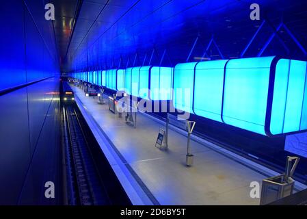 Passagiere, die unter der dramatischen Farbveränderungs-Beleuchtung auf Züge warten Am Bahnhof HafenCity Universität an der U-Bahn Hamburg Stockfoto