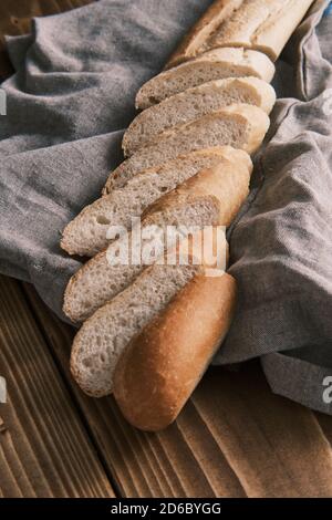 Nahaufnahme frisch geschnittenes französisches Baguette auf einem Leinentuch Auf einem Holztisch Stockfoto