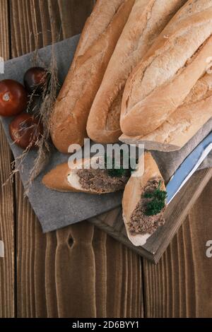 Draufsicht frisches französisches Baguette in Scheiben geschnitten mit Foie Gras Tomate Und Petersilie auf einem Holztisch Stockfoto