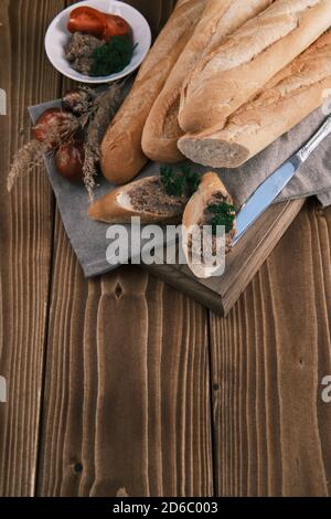 Draufsicht frisches französisches Baguette in Scheiben geschnitten mit Foie Gras Tomate Und Petersilie auf einem Holztisch Stockfoto
