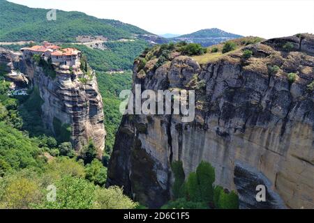 Meteora Land im Himmel: Große alte Stadt von Meteora in Griechenland. Bäume, alte Häuser, blauer Himmel und weiße Wolken. Stockfoto