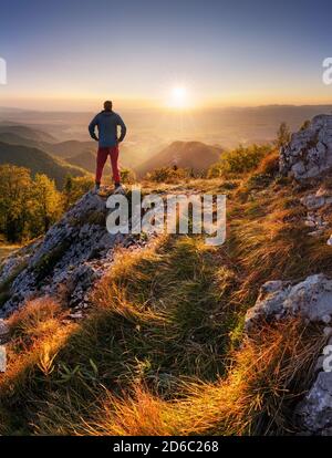 Rückansicht Silhouette des jungen Reisenden Mann stehend mit Schöner Morgenaufgang der Berglandschaft Stockfoto