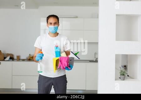 Reinigungs-, Gesundheits- und Hygienekonzept - indischer Mann trägt schützende medizinische Maske zum Schutz vor Viruserkrankungen in Handschuhen mit Waschmittel und Mopp Stockfoto