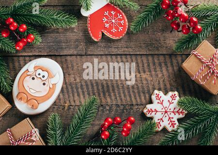 Weihnachtshintergrund mit Lebkuchenbulle, Fäustling, Schneeflocke, Tannenzweig auf Holzhintergrund. Frohe weihnachtskarte. Neujahr 2021. Leerzeichen für Text Stockfoto