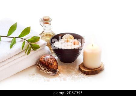 Spa, Schönheit und Wellness Hintergrund. Handtuch, kosmetisches Massageöl, Blatt, Meersalz mit Muscheln und Kerze. Isoliert auf weißem Hintergrund. Stockfoto