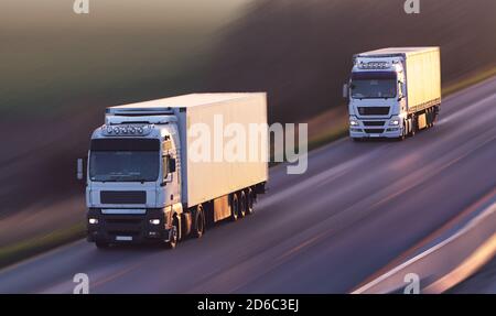 LKW fahren auf der Asphaltstraße in ländlicher Landschaft bei Sonnenuntergang Stockfoto