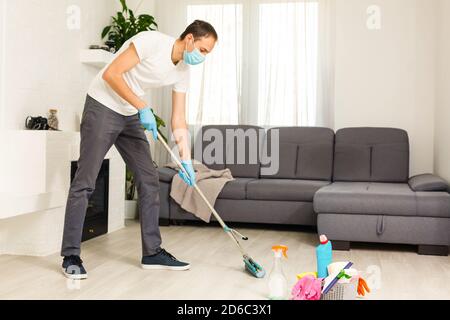 Reinigungs-, Gesundheits- und Hygienekonzept - indischer Mann trägt schützende medizinische Maske zum Schutz vor Viruserkrankungen in Handschuhen mit Waschmittel und Mopp Stockfoto