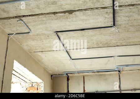 Elektrokabel in einer Schutzwellung an der Decke und an der Wand in einem Raum, in dem Bauarbeiten durchgeführt werden. Stockfoto