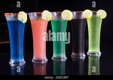 Zuckerfreie Mocktails in verschiedenen Farben in hohen Gläsern mit Limettenkeil. Schwarzer Hintergrund Stockfoto